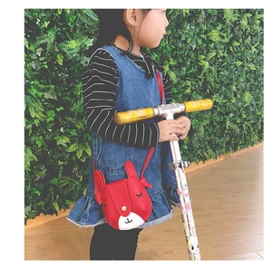 Close-up of a little girl wearing a red cute rabbit-shaped crossbody bag outdoors