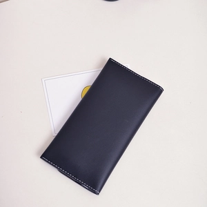 Classic black leather long wallet for women with white contrast stitching on flat surface