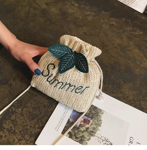 Dettaglio della borsa a secchiello intrecciata crema con ricamo Summer e foglie