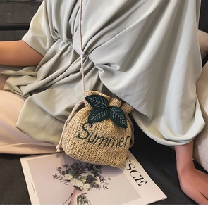 Dettaglio borsa a secchiello in paglia intrecciata con foglie e ricamo Summer
