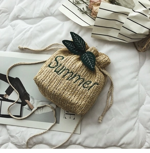 Dettaglio della borsa a secchiello intrecciata con ricamo Summer e decori a foglia verde