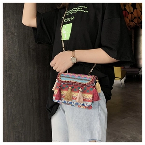 Detail einer Boho-Webtasche mit bunten Quasten und einer goldenen Ketten-Schulterriemen