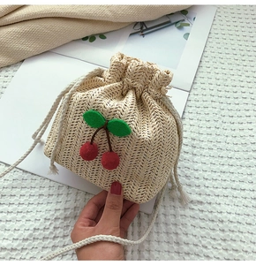 Dettaglio della borsa a secchiello in paglia con ciliegie 3D e chiusura a coulisse bianca