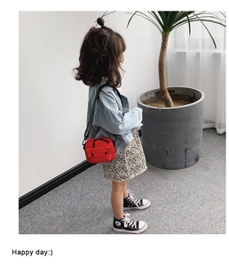 Detail of red canvas kids crossbody bag featuring metal snap pocket and black zipper