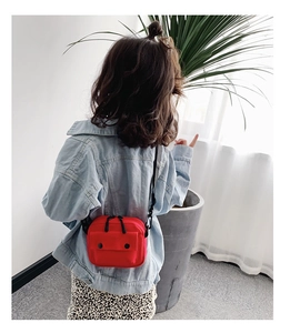 Detail view of red kids canvas crossbody bag with dual buttons and adjustable strap