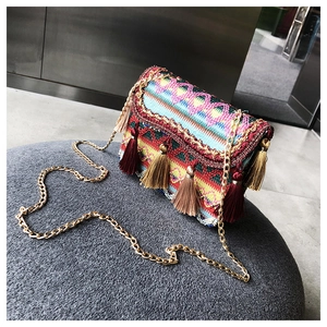Makro-Detail einer Ethno-Stickerel-Tasche mit bunten Quasten und goldener Kettenriemen