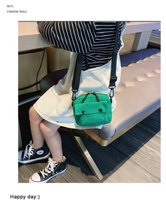Detail view of green canvas crossbody bag with adjustable strap and dual zippers