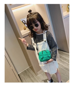Detail of green kids canvas crossbody bag featuring front flap pocket and adjustable strap