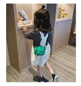 Close-up of bright green canvas crossbody bag for kids with adjustable black strap