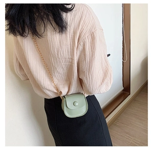Upper body view of a little girl wearing a mini light green crossbody bag with gold chain