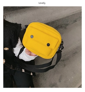 Detail of child wearing a bright yellow canvas crossbody bag with black buckle accents