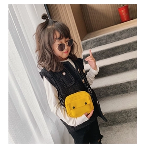 Detail of yellow canvas crossbody bag for kids featuring adjustable strap and front pocket