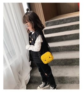 Detailed view of child modeling a bright yellow canvas crossbody bag in stylish outfit