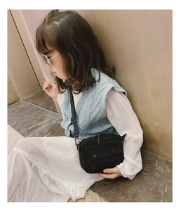 Detail of small black canvas crossbody bag with adjustable strap on a child model