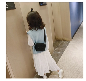 Rear view of a child wearing a black canvas crossbody bag in a modern hallway
