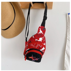 Gros plan sur la sacoche dinosaure en toile rouge avec broderie et détails de fermeture
