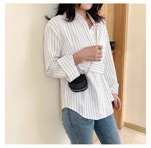 Detail of white wrap shirt with black vertical stripes and trendy crossbody chain bag