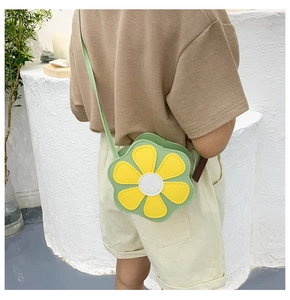 Detail view of sunflower shaped crossbody bag for kids with green strap on a model