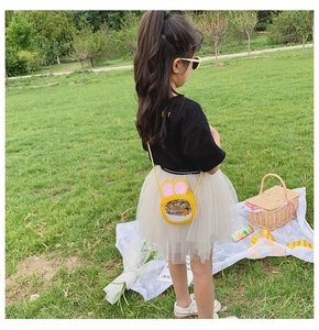 Close-up of cute yellow bunny ear crossbody bag with sequins and carrot decor on grass