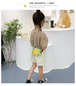 Rear view of a child wearing a green daisy-shaped crossbody bag in a stylish setting