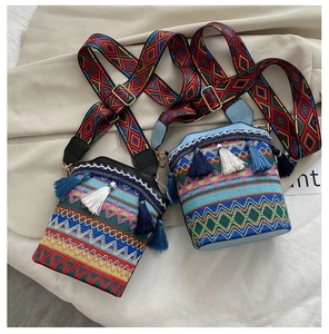 Dettaglio borsa a secchiello etnica intrecciata con nappe e motivi geometrici colorati