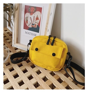 Detail of a bright yellow canvas crossbody bag with double zippers and black strap