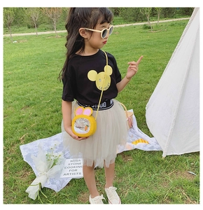 Outdoor shot of a girl wearing a black T-shirt and grey tutu with a yellow rabbit sequin bag