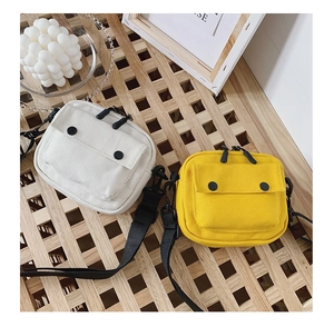 Detail of minimalist kids canvas crossbody bags in cream and yellow with adjustable straps