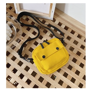 Macro detail of yellow canvas shoulder bag with dual zippers and front pocket