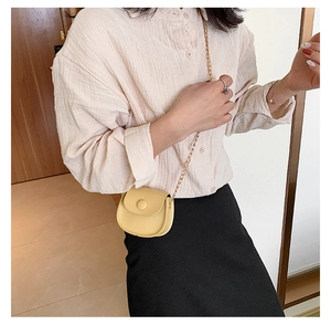 Detail of yellow mini round crossbody bag with gold chain strap shown on model
