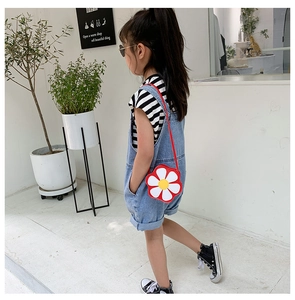 Close-up of a vibrant red flower-shaped crossbody bag on a child's denim summer outfit