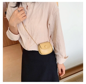 Girl's beige mini saddle bag featuring a fine gold chain strap and smooth faux leather finish
