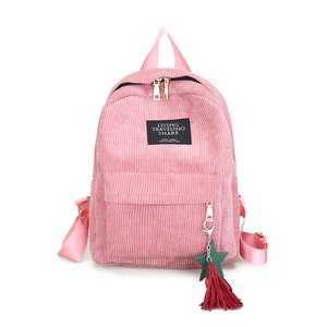 Pink corduroy backpack with green star and red tassel charm on a clean white background
