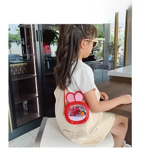 Detail view of red rabbit shoulder bag with sequins and carrot charm on a young child