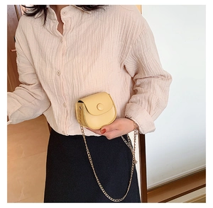 Girl wearing a trendy yellow mini crossbody bag with a round snap and metal chain