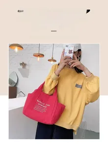 Detail of red canvas tote bag with 'Natural free oneself' text worn by model