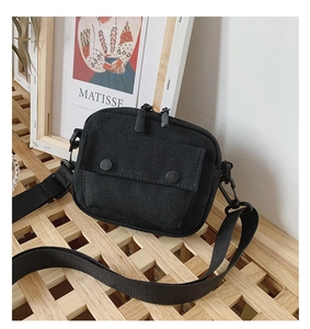Close-up of black canvas crossbody bag featuring dual zippers and adjustable wide strap