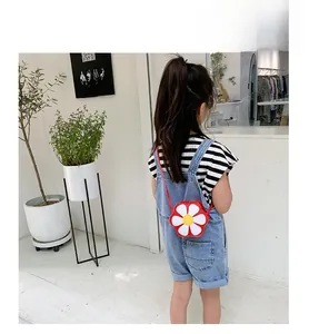 Close-up of a child wearing a red daisy flower crossbody bag with a striped T-shirt