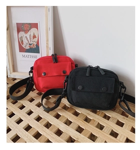 Close-up of red and black canvas crossbody bags with metal snaps and zip closure