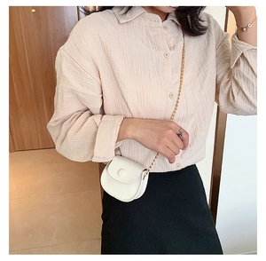 Close-up of a white mini semi-circle crossbody bag with a fine gold chain strap