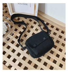 Detail of minimalist black canvas crossbody bag with front flap pocket and dual snaps