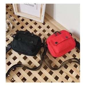 Detail of red and black canvas crossbody bags with snap pockets and adjustable straps