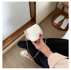 Detailed view of mini white semicircular chain bag with gold metal strap and magnetic flap