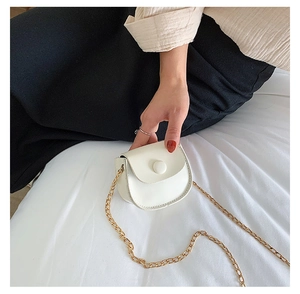 Detail of white faux leather mini saddle bag with gold metal chain and snap closure