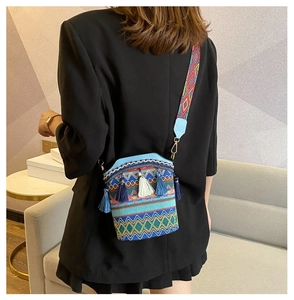 Dettaglio borsa a secchiello boho con ricami colorati, nappe e tracolla intrecciata