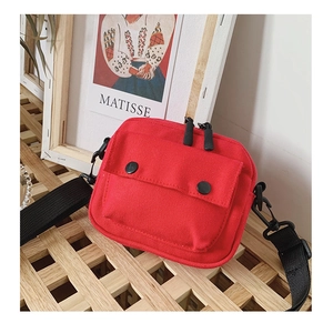 Detail of red canvas kids shoulder bag showing dual zipper and front snap pocket