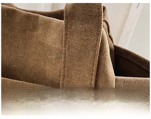 Detailed close-up of brown canvas tote bag stitching with free typography printing