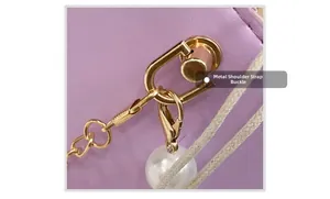 Close-up of golden hardware buckle with chain and white pearl on purple leather bag