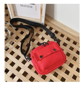 Detail of red canvas kids crossbody bag with double snap pockets and black strap