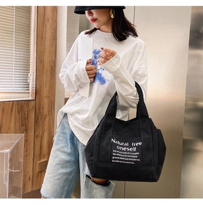 Lifestyle shot of large black canvas tote bag with white lettering and sturdy handles